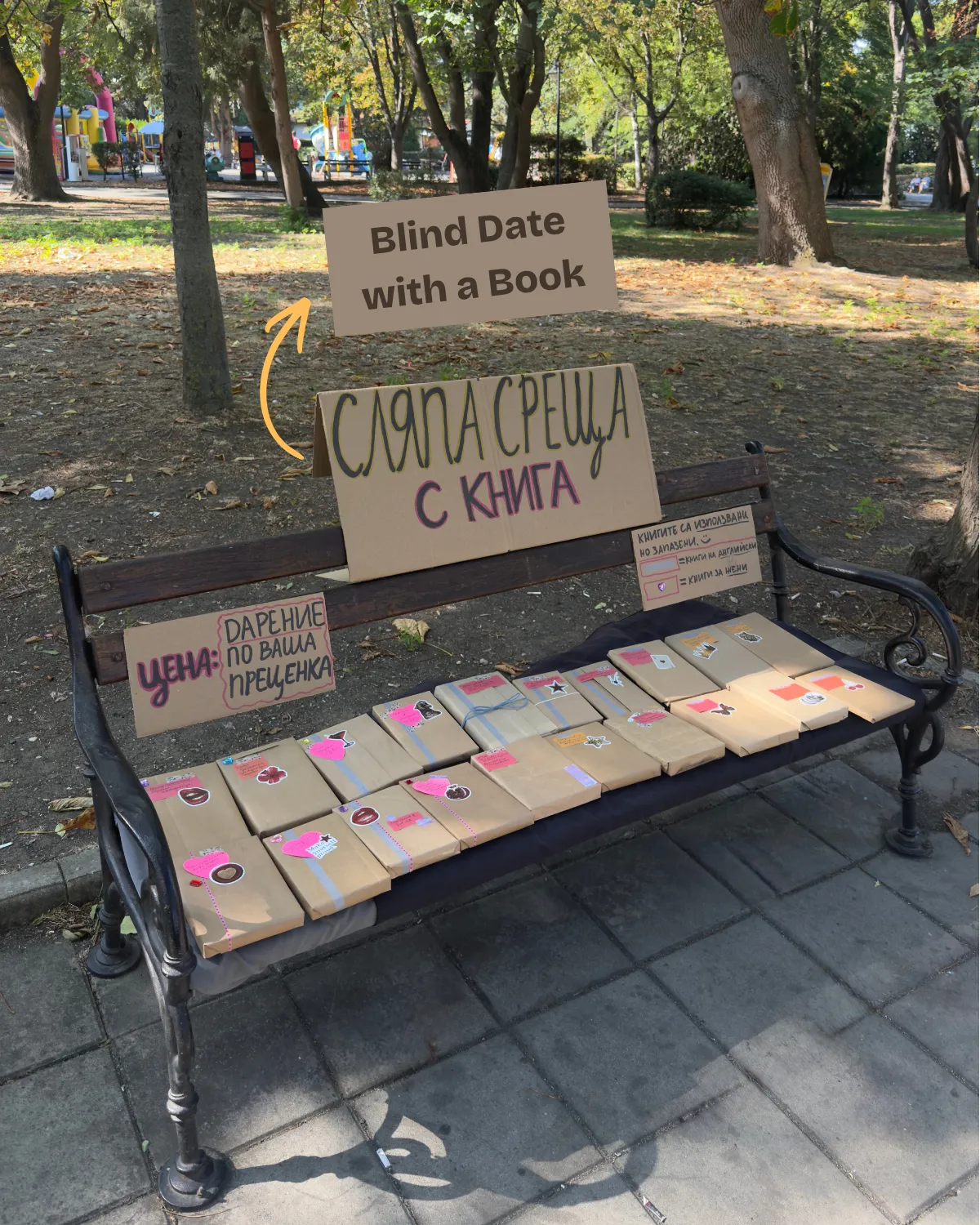 Пейка в парка с опаковани книги и табела „Сляпа среща с книга“